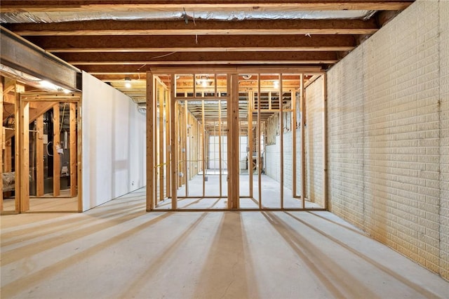 misc room featuring brick wall and concrete flooring