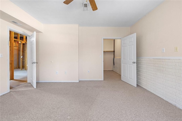 spare room with ceiling fan, brick wall, and light carpet