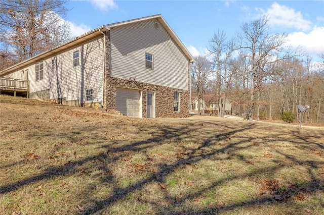 view of property exterior featuring a garage, a deck, and a lawn