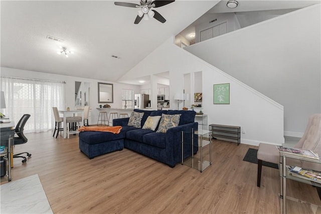 living room featuring light hardwood / wood-style flooring, high vaulted ceiling, and ceiling fan