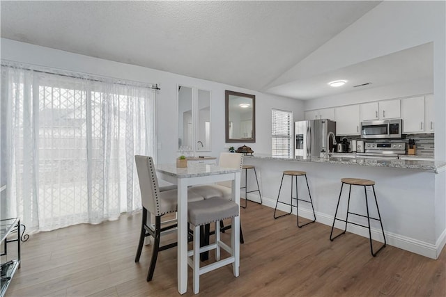 dining room with vaulted ceiling and light hardwood / wood-style flooring