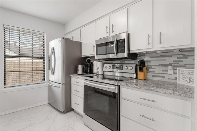 kitchen with white cabinetry, light stone counters, decorative backsplash, and appliances with stainless steel finishes