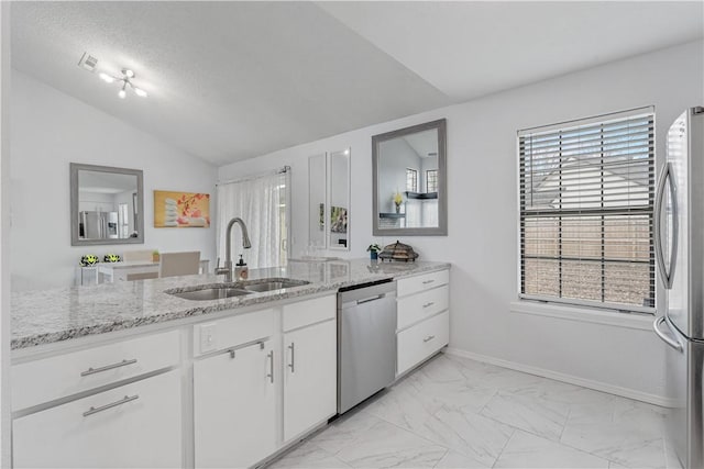 kitchen with lofted ceiling, sink, white cabinets, stainless steel appliances, and light stone countertops