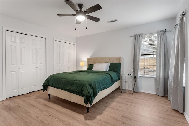 bedroom with multiple closets, ceiling fan, and light wood-type flooring