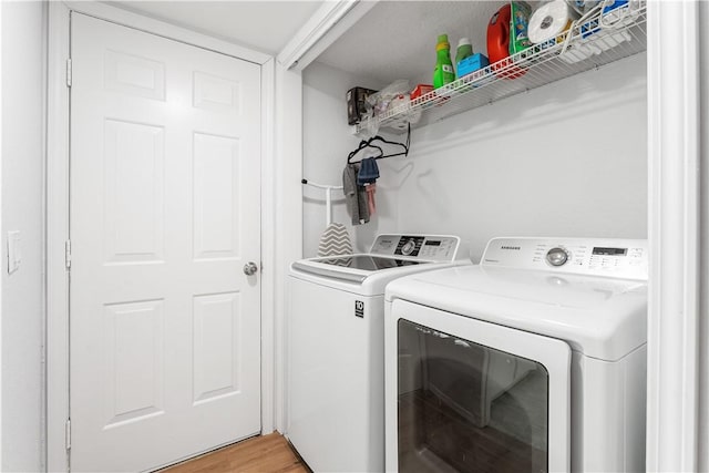 laundry area with washer and dryer and light hardwood / wood-style floors