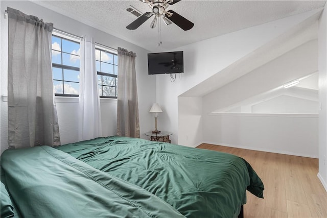 bedroom featuring a textured ceiling, ceiling fan, and light hardwood / wood-style flooring