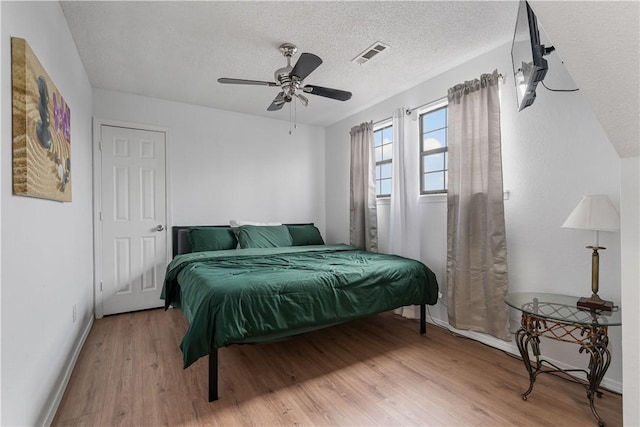 bedroom featuring light wood-type flooring, a textured ceiling, and ceiling fan