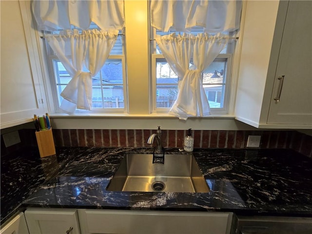 kitchen featuring white cabinetry, sink, and dark stone counters