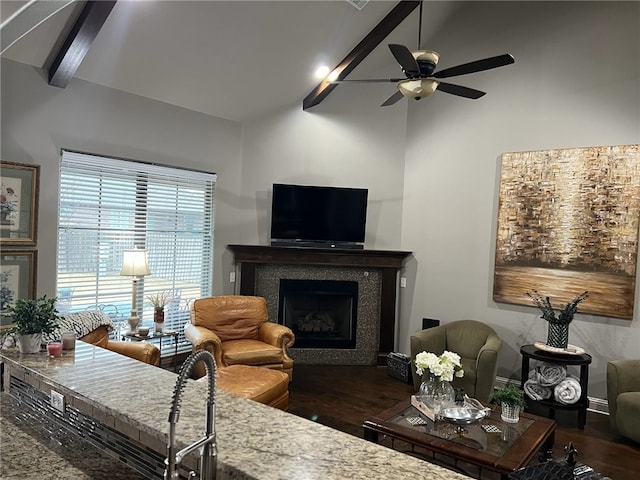 living room with vaulted ceiling with beams, dark wood-type flooring, a tile fireplace, and ceiling fan