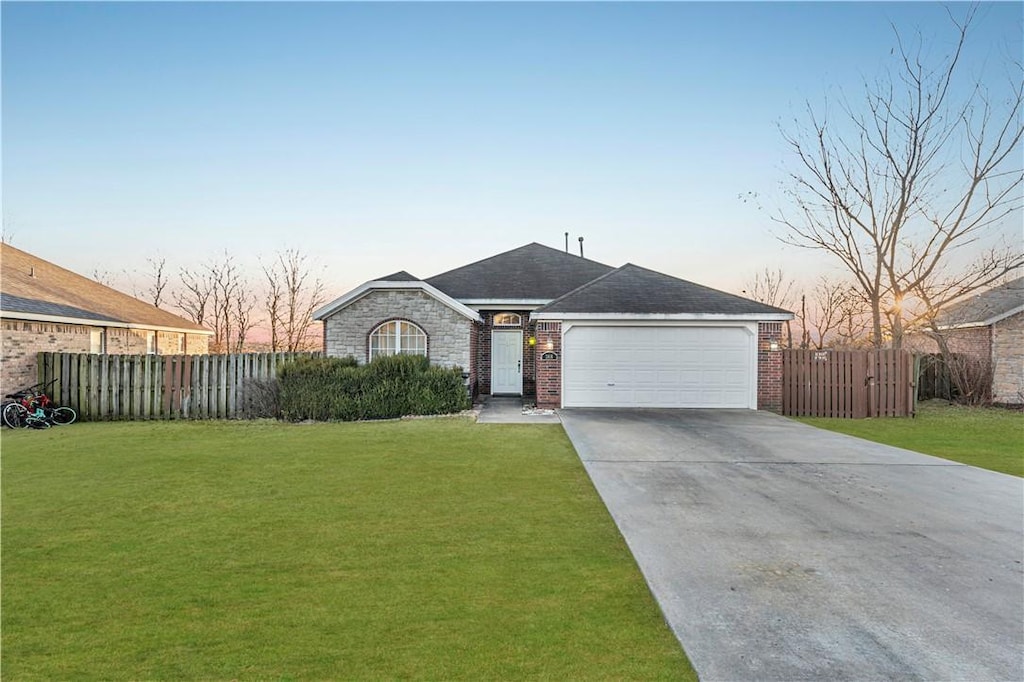 ranch-style house with a garage and a lawn