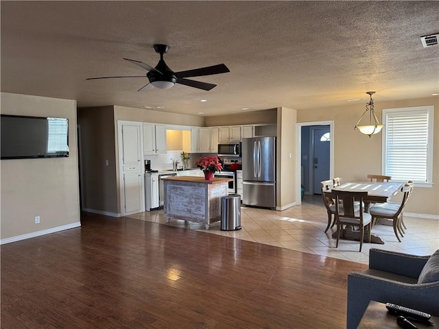 kitchen featuring pendant lighting, white cabinets, ceiling fan, light hardwood / wood-style floors, and stainless steel appliances