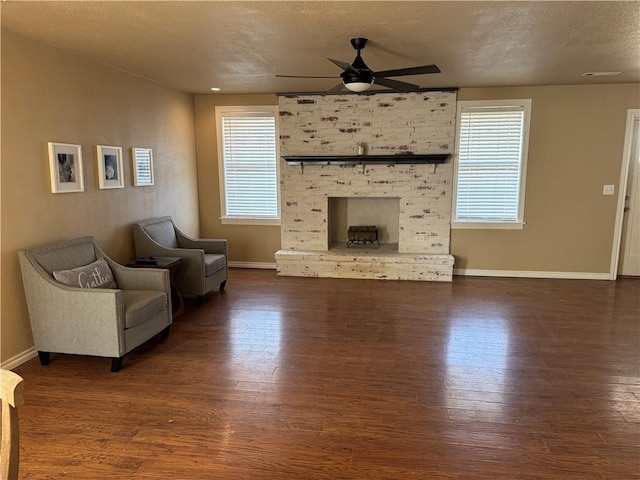 living room with dark wood-type flooring, a wealth of natural light, and a fireplace