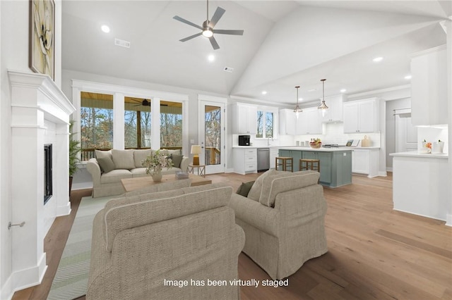 living room featuring ceiling fan, high vaulted ceiling, and light hardwood / wood-style floors