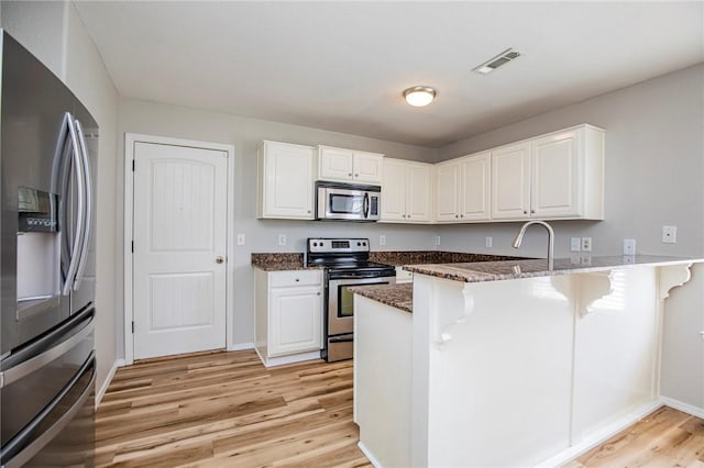 kitchen featuring white cabinetry, appliances with stainless steel finishes, and kitchen peninsula