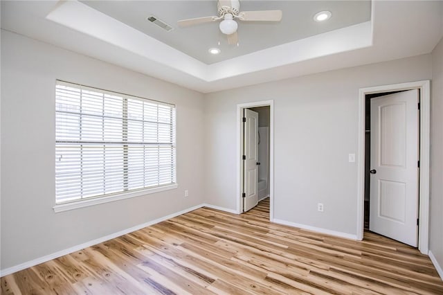 unfurnished bedroom with a raised ceiling, ceiling fan, and light hardwood / wood-style flooring