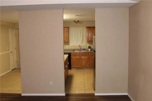 kitchen with sink, black dishwasher, and light tile patterned flooring