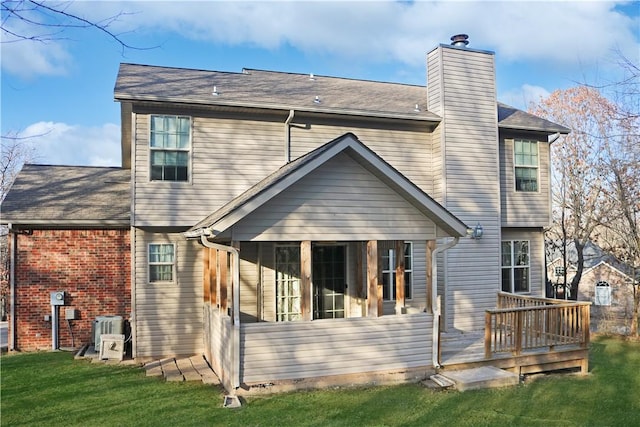 rear view of house featuring a sunroom, a wooden deck, a chimney, central AC unit, and a lawn