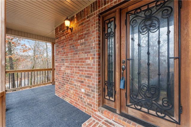 doorway to property with a porch, brick siding, and french doors