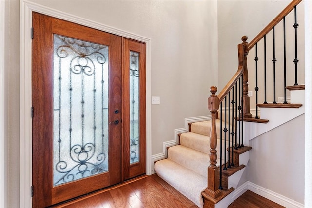 entryway with wood finished floors, stairway, and baseboards