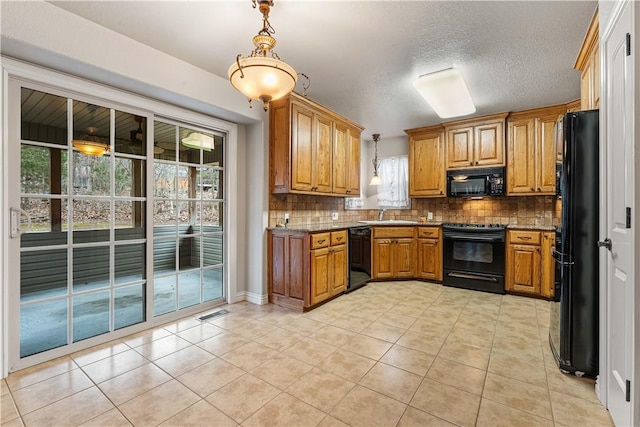 kitchen featuring black appliances, healthy amount of natural light, brown cabinets, light tile patterned floors, and a textured ceiling