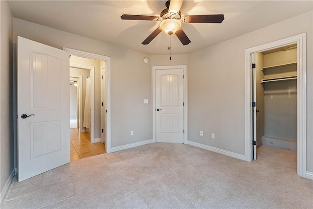 unfurnished bedroom featuring light carpet, a walk in closet, baseboards, and a closet