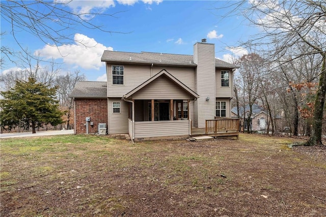 back of property with a chimney, a lawn, a sunroom, a deck, and brick siding
