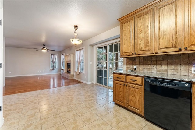 kitchen featuring dishwasher, backsplash, a warm lit fireplace, and a ceiling fan