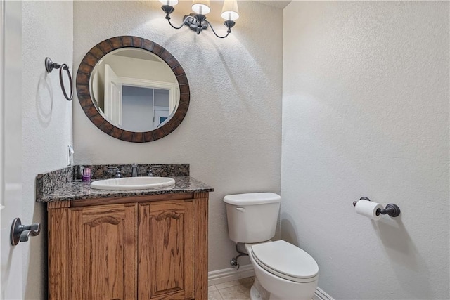 half bath with toilet, vanity, baseboards, and tile patterned floors