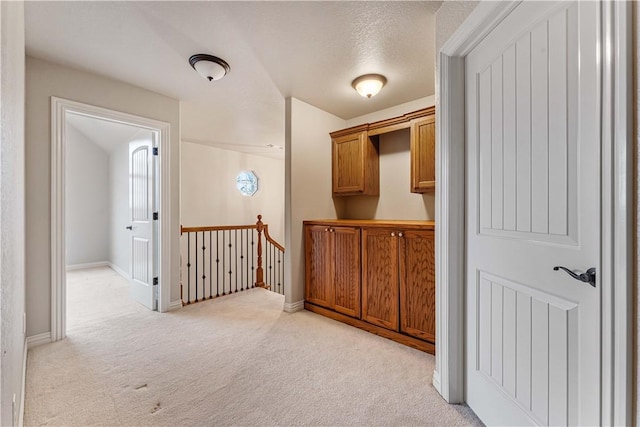 hall featuring light colored carpet and a textured ceiling