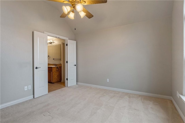 unfurnished bedroom with ensuite bath, vaulted ceiling, light colored carpet, and ceiling fan