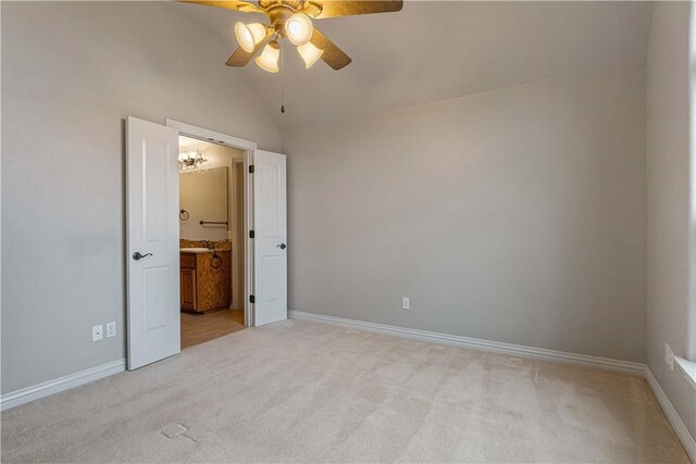 unfurnished bedroom featuring light colored carpet, lofted ceiling, baseboards, ensuite bathroom, and ceiling fan