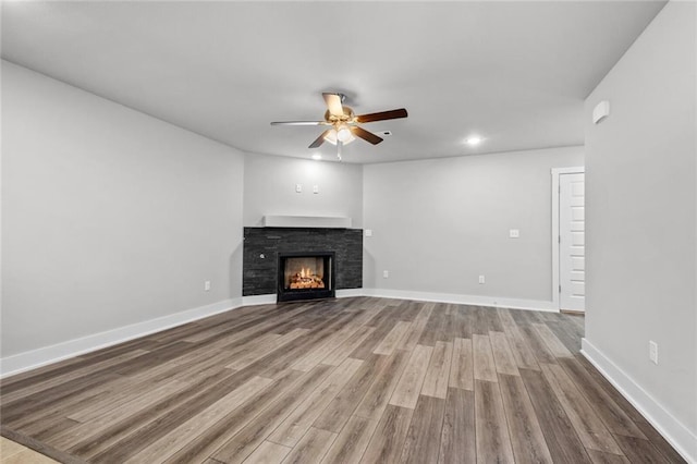 unfurnished living room with wood-type flooring, a fireplace, and ceiling fan