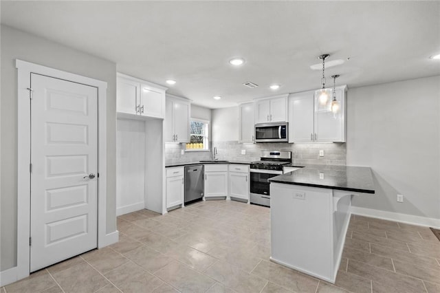 kitchen with a breakfast bar area, appliances with stainless steel finishes, white cabinets, decorative light fixtures, and kitchen peninsula