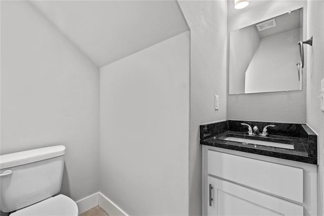 bathroom with vaulted ceiling, vanity, and toilet