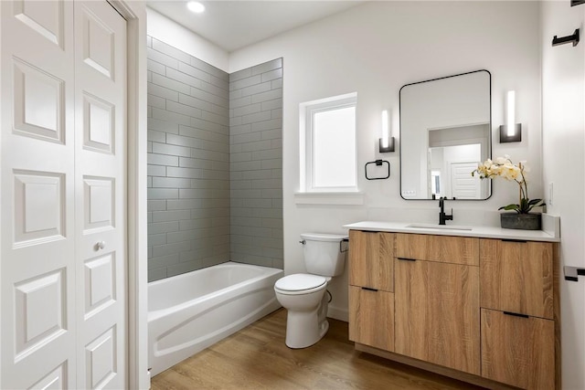 full bathroom featuring tiled shower / bath combo, toilet, hardwood / wood-style flooring, and vanity