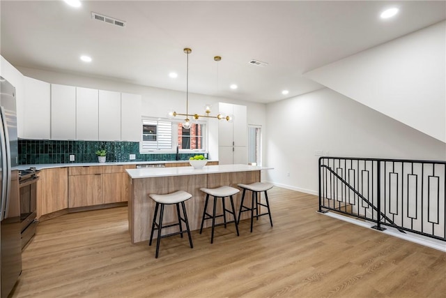 kitchen with a kitchen island, light wood-type flooring, and white cabinets