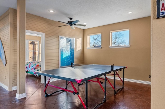 playroom with dark tile patterned flooring, ceiling fan, a textured ceiling, and wood walls