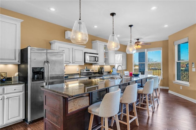 kitchen featuring appliances with stainless steel finishes, an island with sink, sink, a breakfast bar area, and white cabinets