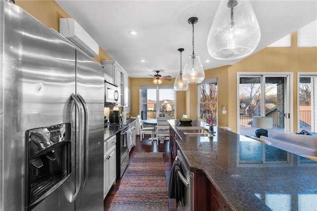 kitchen featuring pendant lighting, sink, dark stone countertops, stainless steel appliances, and a wall mounted AC