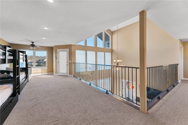 corridor featuring an inviting chandelier, carpet floors, and a textured ceiling