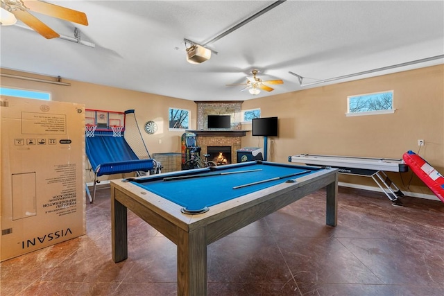 game room with a healthy amount of sunlight, a fireplace, ceiling fan, and billiards