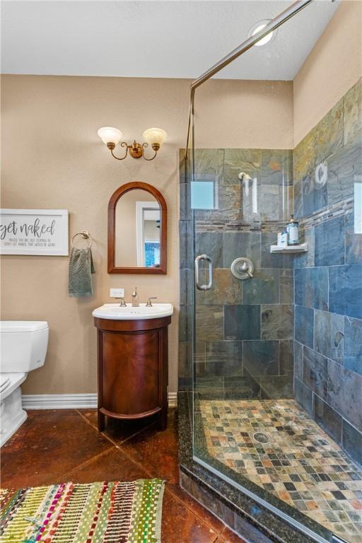 bathroom with tile patterned floors, vanity, toilet, and a shower with shower door