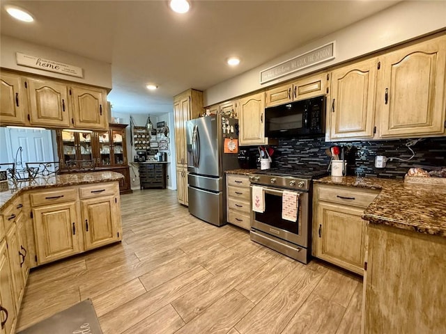 kitchen featuring tasteful backsplash, light brown cabinets, dark stone counters, and appliances with stainless steel finishes