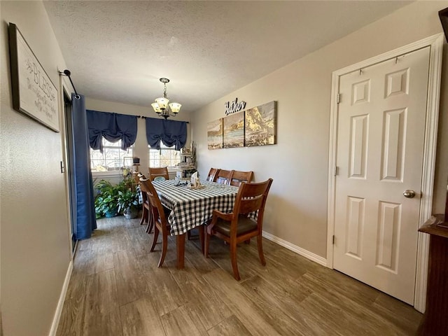 dining room featuring a textured ceiling, wood-type flooring, and a chandelier