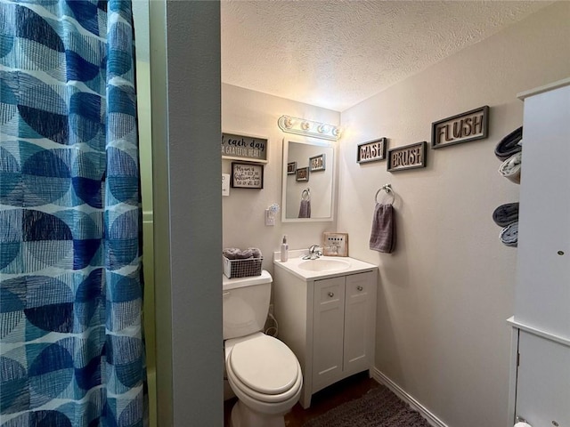 bathroom with vanity, toilet, curtained shower, and a textured ceiling