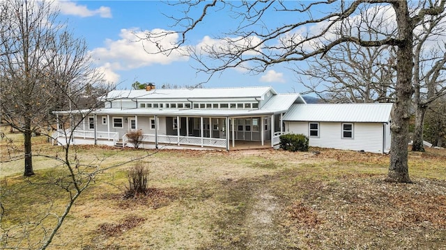 rear view of house featuring a sunroom and a lawn