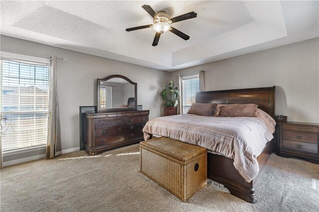 bedroom with baseboards, a tray ceiling, a textured ceiling, and light colored carpet