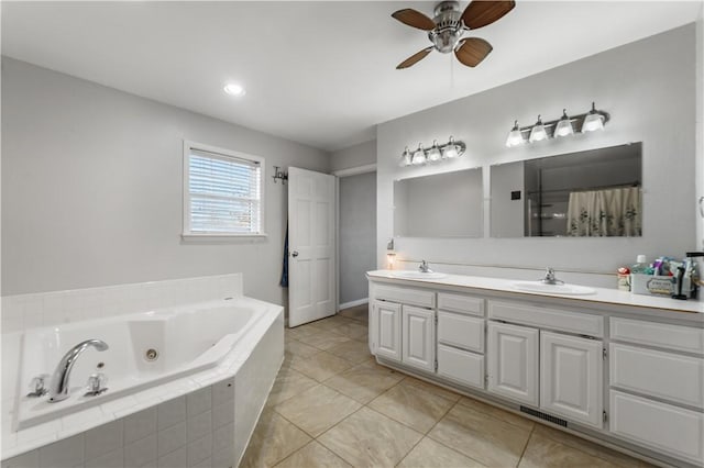 bathroom with double vanity, a tub with jets, a sink, and a ceiling fan