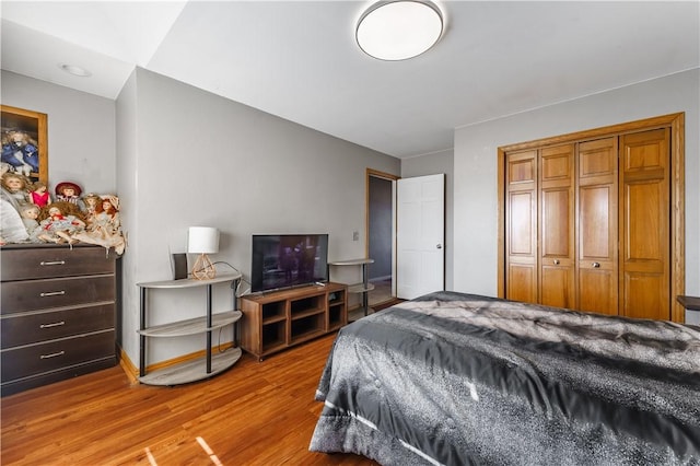 bedroom with light wood-style floors, baseboards, and a closet