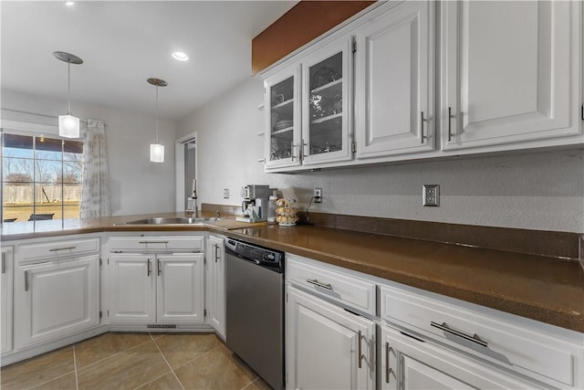 kitchen featuring stainless steel dishwasher, glass insert cabinets, dark countertops, and white cabinetry